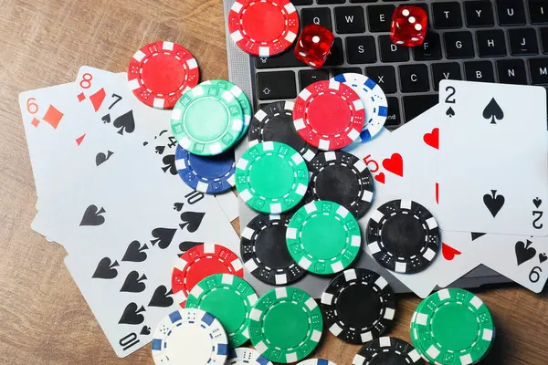 Poker fişleri, dizüstü bilgisayar, iskambil kağıtları, tahta masa, düz yatak. Çevrimiçi oyun