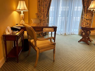 Rahat mobilyalar ve geniş pencereli şık bir otel odası.