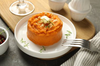 Gri desenli masada servis edilen lezzetli patates püresi, tereyağı, kekik ve ceviz tabağı, yakın plan.