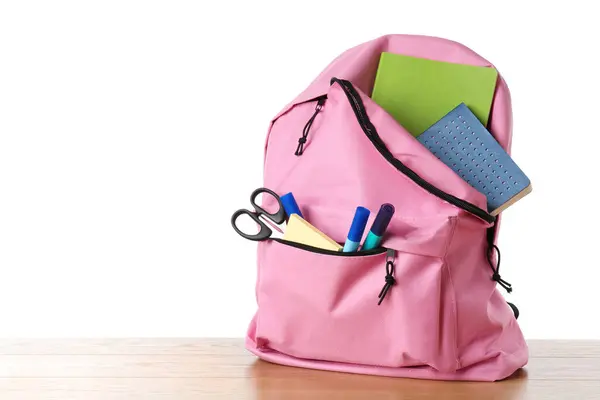 stock image Backpack with different school stationery on wooden table against white background, space for text