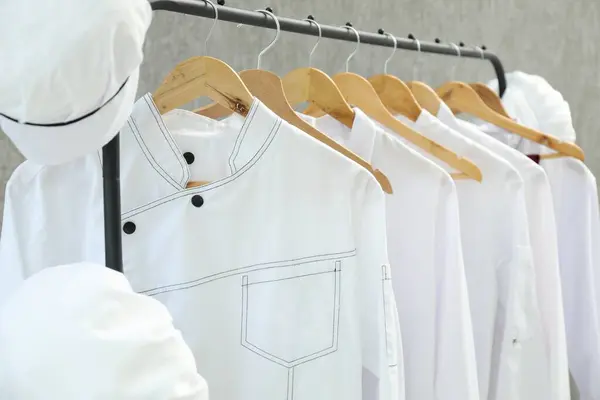 stock image Chefs' uniforms on clothing rack against grey background, closeup