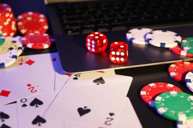 Çevrimiçi poker. Siyah masada kart, fiş, zar ve dizüstü bilgisayar oynanıyor.