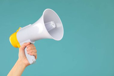 Mavi arka planda megafon hoparlörü tutan kadın, yakın plan. Metin için boşluk