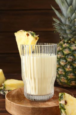 Bardakta lezzetli ananas püresi ve ahşap masada meyve dilimleri, yakın plan.