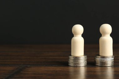 Finansal eşitlik. Masada da benzer miktarda bozuk para bulunan tahta figürler. Metin için boşluk