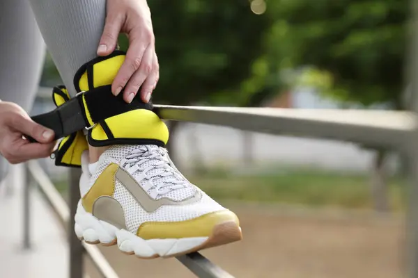 stock image Woman putting on ankle weights outdoors, closeup