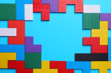 Açık mavi zemin üzerinde renkli ahşap yapboz parçaları, üst manzara. Metin için boşluk