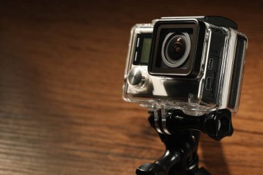 Ahşap yüzeyde modern aksiyon kamerası ve tripod, yakın plan. Metin için boşluk