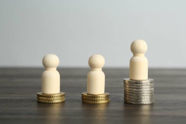 Finansal eşitsizlik. Ahşap masada insan figürleri ve madeni paralar