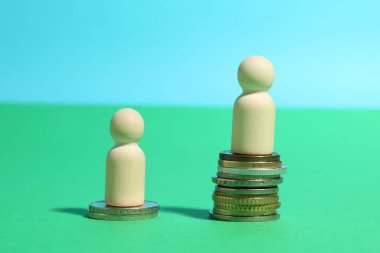 Finansal eşitsizlik. Renk arkaplanındaki bir tahta para yığını diğerinden daha büyük.