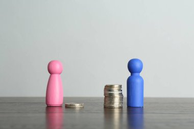 Finansal eşitsizlik. Erkek ve kadın figürleri ahşap masanın üzerinde dengesiz miktarda madeni para var.