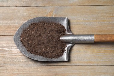 Tahta masanın üzerinde toprak olan metal kürek, üst manzara.