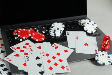 Çevrimiçi poker. Açık gri masada kart, fiş, zar ve dizüstü bilgisayar oynamak