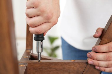 Tornavidalı bir adam mobilyaları içeride monte ediyor.