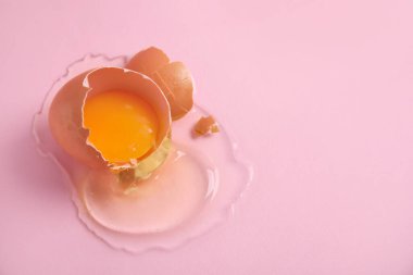 Kırık çiğ yumurta, pembe arka planda kabuk, yakın plan. Metin için boşluk