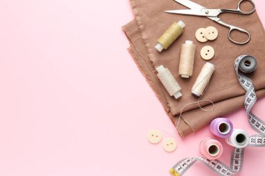 Düz kompozisyon ve pembe arka planda farklı dikiş malzemeleri. Metin için boşluk