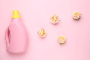 Bir şişe çamaşır deterjanı ve pembe arka planda çiçekler, yakın plan.
