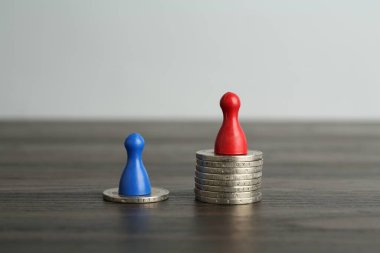 Finansal eşitsizlik. Ahşap masada insan figürleri ve madeni paralar