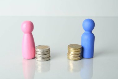 Finansal eşitsizlik. Işık masasında bozuk paraları olan erkek ve kadın figürleri