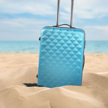 Denize yakın kumsalda açık mavi bir bavul.