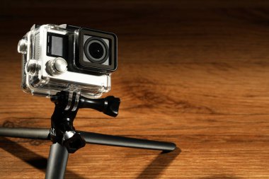 Ahşap yüzeyde modern aksiyon kamerası ve tripod. Metin için boşluk