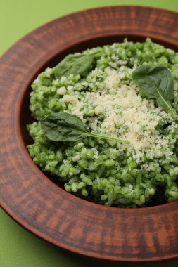 Açık yeşil arka planda parmesan peynirli lezzetli ıspanaklı risotto.