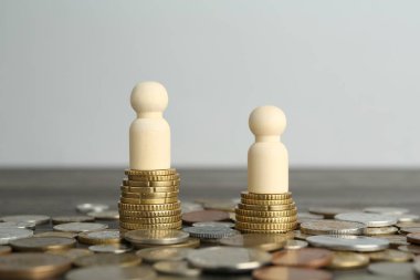 Finansal eşitsizlik. Ahşap masada insan figürleri ve madeni paralar