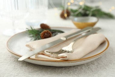 Tabak, çatal bıçak, köknar dalları ve kozalaklı Noel sofrası, yakın plan.