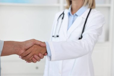 Hastanedeki hastayla el sıkışan doktor, yakın plan.