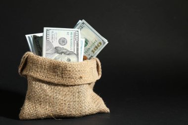 Koyu arkaplanda çuval içinde dolar banknotları, metin için boşluk