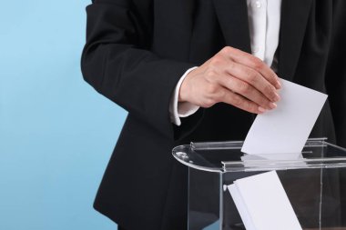 Kadın oyunu açık mavi arka plana karşı sandığa koyuyor, yakın plan.