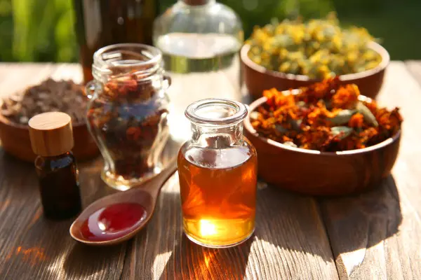 stock image Different tinctures and ingredients on wooden table outdoors