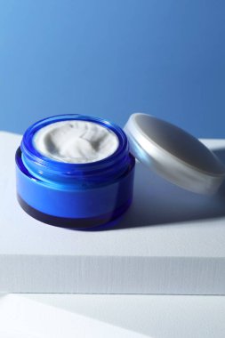 Açık mavi arkaplana karşı kavanozdaki yüz kreminin şık sunumu