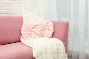 Dekoratif yastıklar ve pembe kanepede pofuduk battaniye.