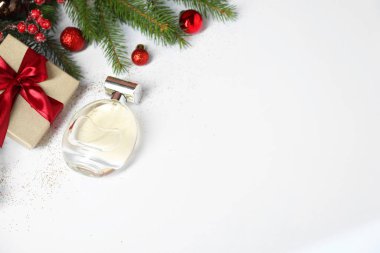 Beyaz arka planda parfüm şişesi olan Noel kompozisyonu, manzaranın üstünde. Metin için boşluk