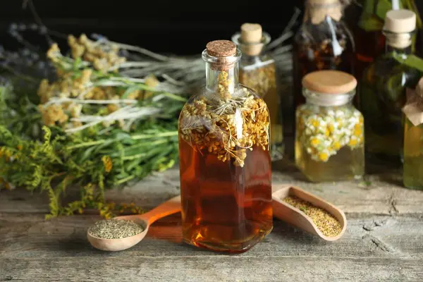 Stock image Different tinctures and herbs on wooden table, closeup