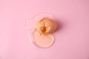 Kırık çiğ yumurta, pembe arka planda kabuk, üst manzara.