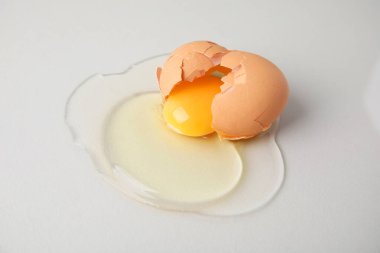 Kırık çiğ yumurta açık gri arka planda, yakın plan.
