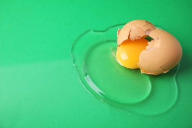 Yeşil arka planda kabuğu olan kırılmış çiğ yumurta, yakın plan. Metin için boşluk