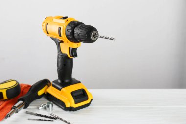 Kablosuz elektrikli matkap, eldivenler, bitler, tornavida ve mezura beyaz ahşap masa üzerinde, metin için boşluk