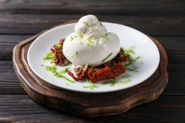 Lezzetli burrata peyniri ve kurutulmuş domatesler ahşap masada, yakın plan.