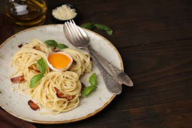 Carbonara makarnası ahşap masada servis ediliyor.