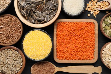 Farklı türde baklagiller, tohumlar ve tahıllar siyah ahşap masa üzerinde, düz yatıyordu.