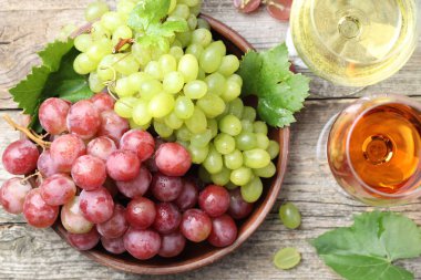 Taze üzümler ve şarap kadehleri ahşap masada, düz yerde.