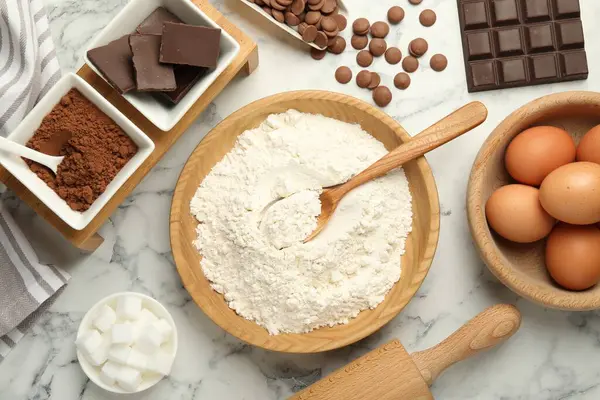 stock image Flat lay composition with flour, chocolate and other ingredients for making dough on white marble table