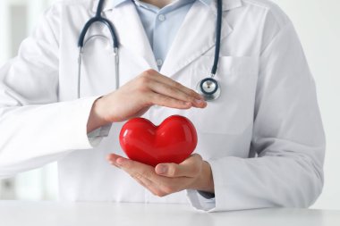 Klinikteki beyaz masada kırmızı kalpli doktor, yakın plan.