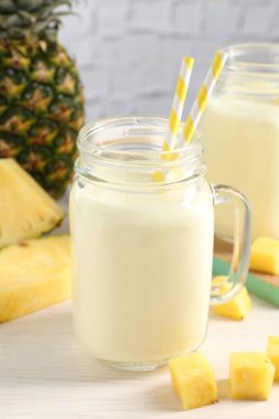 Mason kavanozunda nefis ananas kokteyli ve beyaz ahşap masada taze meyve.