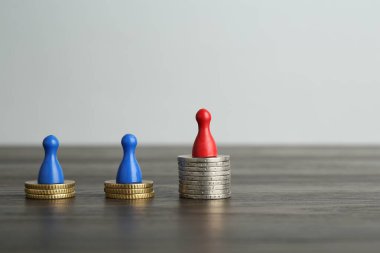 Finansal eşitsizlik. Ahşap masada insan figürleri ve madeni paralar
