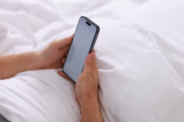 Yatakta akıllı telefon kullanan adam, yakın çekim görüntüsü