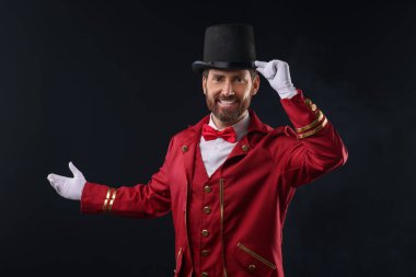 Kırmızı kostümlü ve siyah şapkalı bir şovmen portresi.